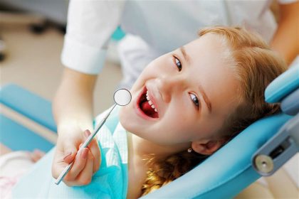 little girl happy sitting in pediatric dentist chair